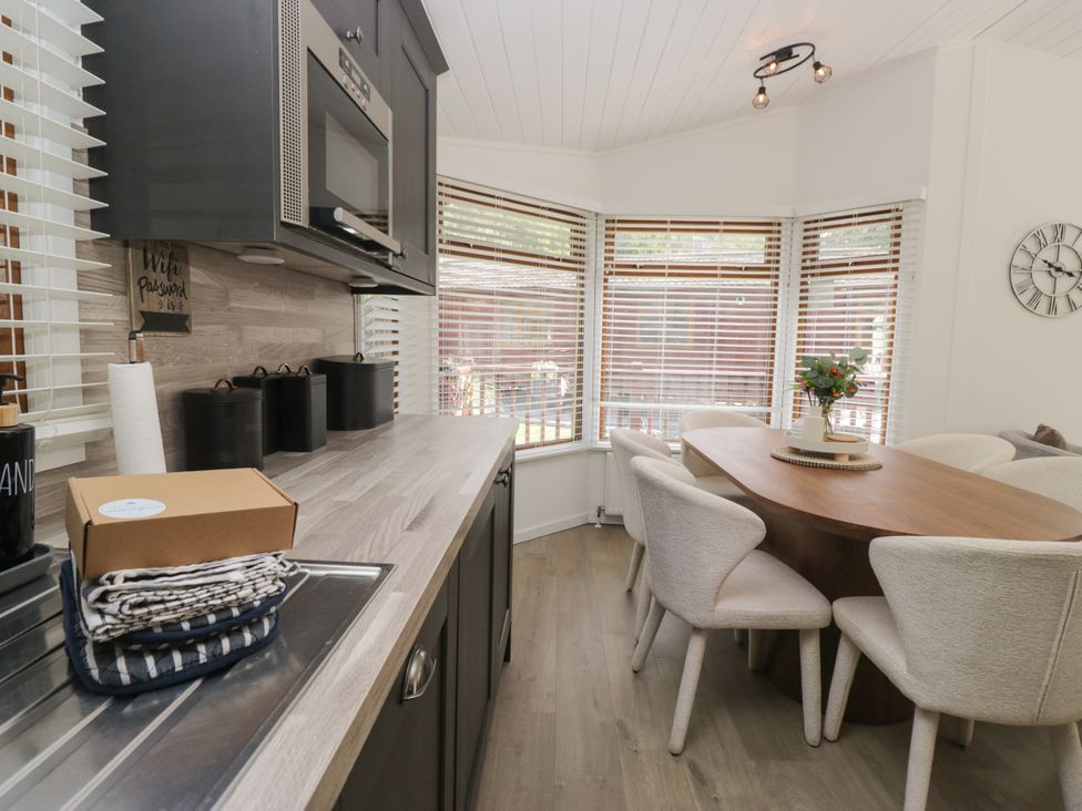 A kitchen with a microwave and dining area at Ruskin Lodge Langdale 16, White Cross Bay near Windermere