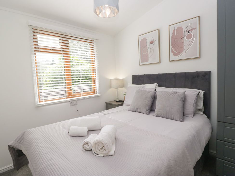 A bedroom with a bed and artwork on the wall at Ruskin Lodge, Langdale 16, White Cross Bay near Windermere