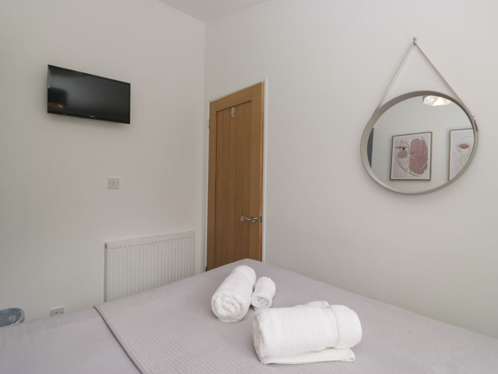 A bedroom with a television and towels on the bed at Ruskin Lodge, Langdale 16, White Cross Bay near Windermere