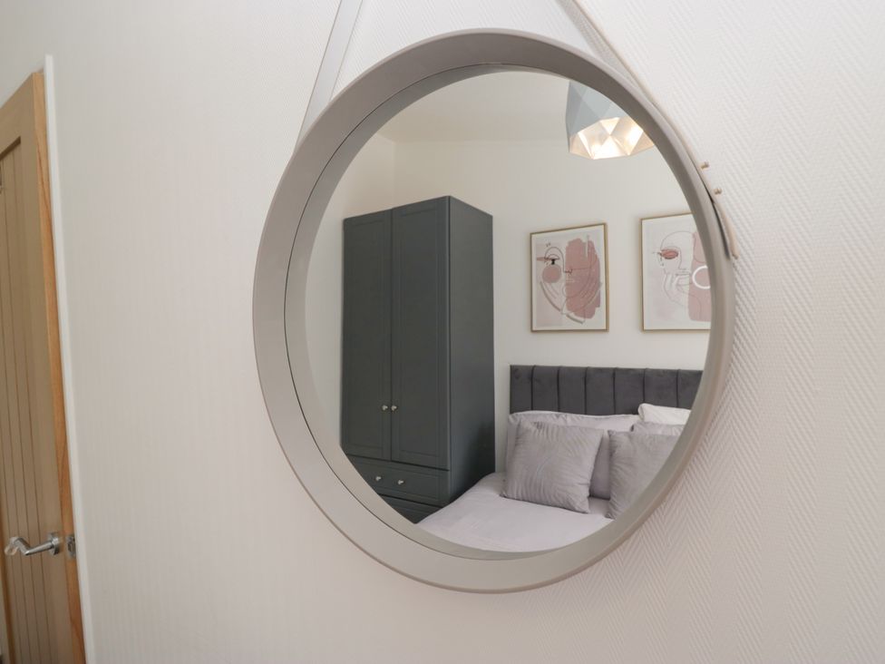 A reflection of a wardrobe and bed in a mirror at Ruskin Lodge, Langdale 16, White Cross Bay near Windermere