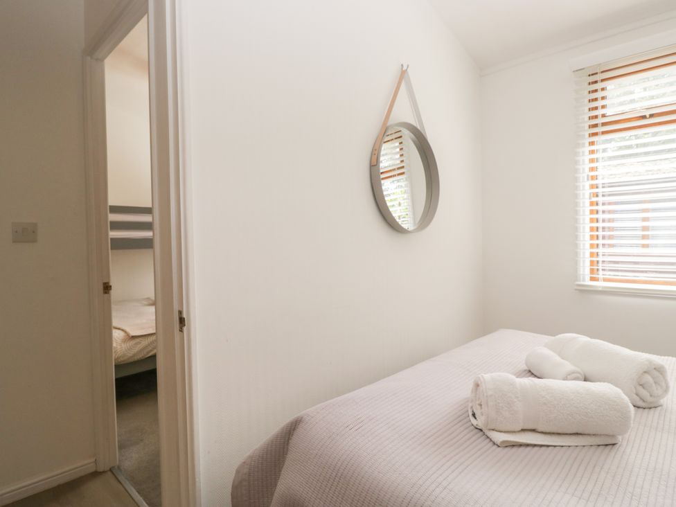 A bedroom with a bed and towels on it at Ruskin Lodge, Langdale 16, White Cross Bay near Windermere