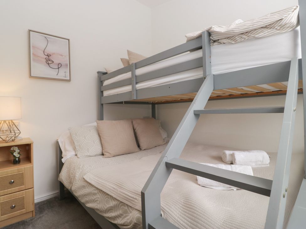A bedroom with a bunk bed and double bed at Ruskin Lodge in Langdale 16, White Cross Bay near Windermere
