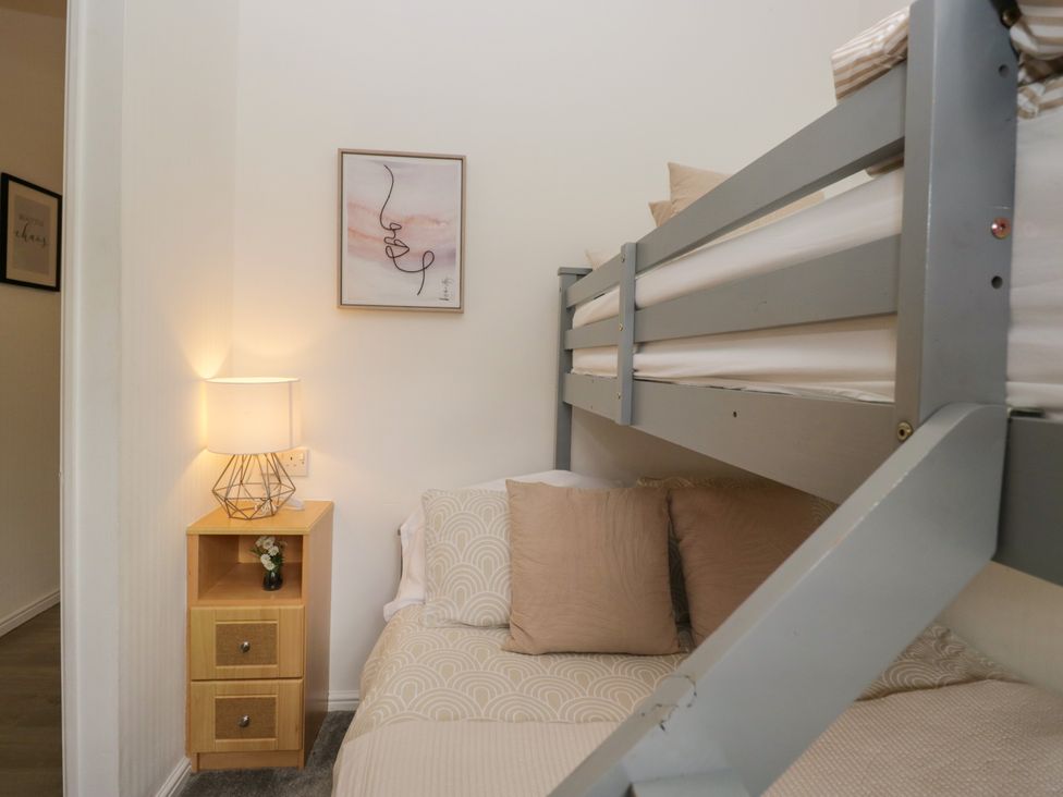 A bedroom with a bunk bed and nightstand at Ruskin Lodge, Langdale 16, White Cross Bay near Windermere