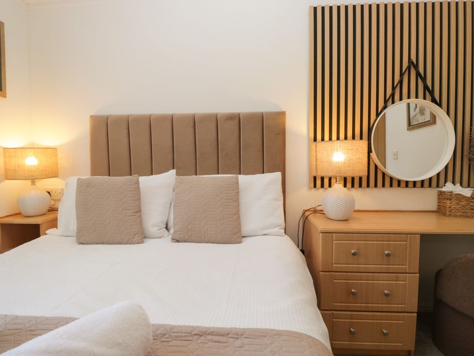 A bedroom with a bed and dresser at Ruskin Lodge, Langdale 16, White Cross Bay near Windermere