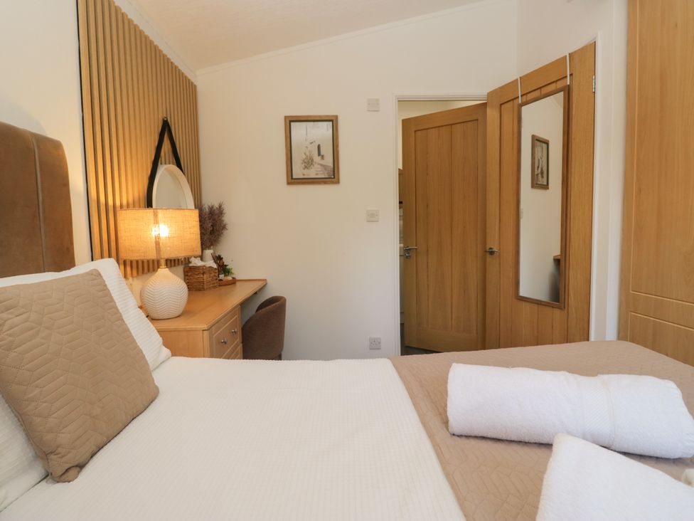 A bedroom with a bed and lamp at Ruskin Lodge Langdale 16 White Cross Bay near Windermere