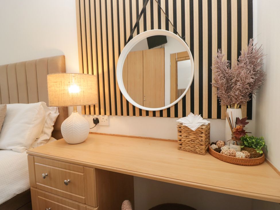 A bedroom with a lamp and mirror on a desk at Ruskin Lodge, Langdale 16, White Cross Bay near Windermere