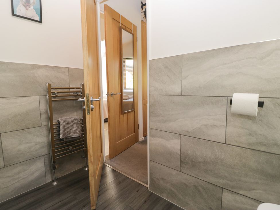 A bathroom with a towel rack and door at Ruskin Lodge, Langdale 16, White Cross Bay near Windermere