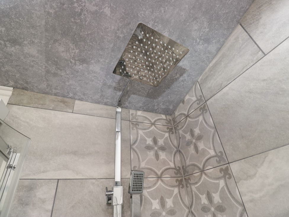 A shower with modern fixtures and patterned tiles at Ruskin Lodge Langdale 16, White Cross Bay near Windermere