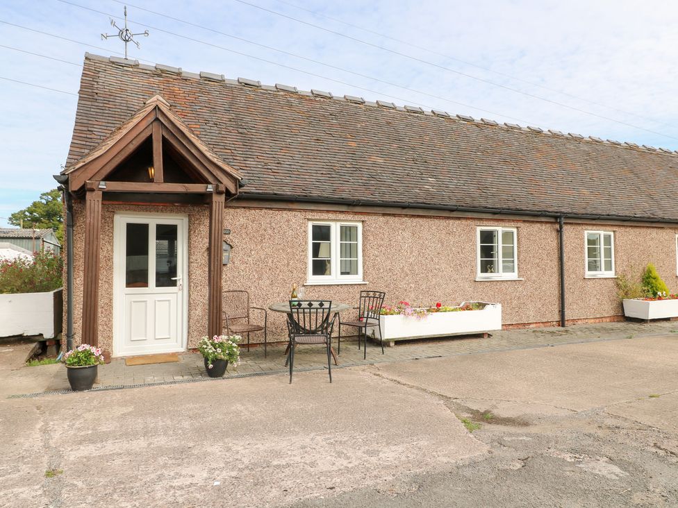 An outdoor area with a table and chairs in front of a house at The Hereford Lodge in Great Haywood