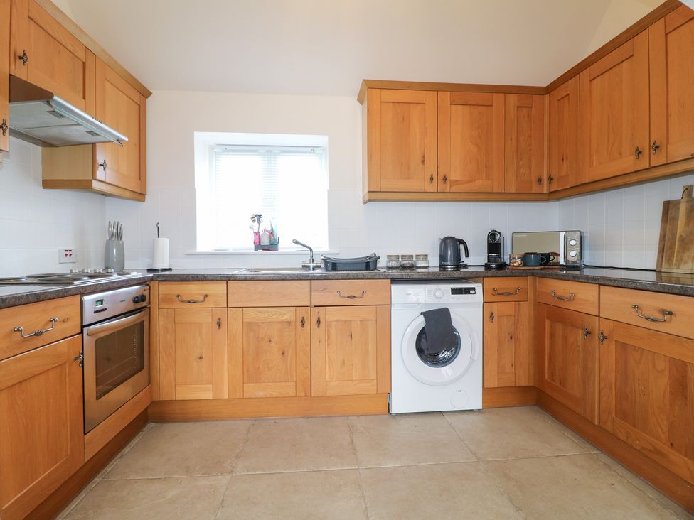 A kitchen with wooden cabinets and appliances at The Hereford Lodge in Great Haywood