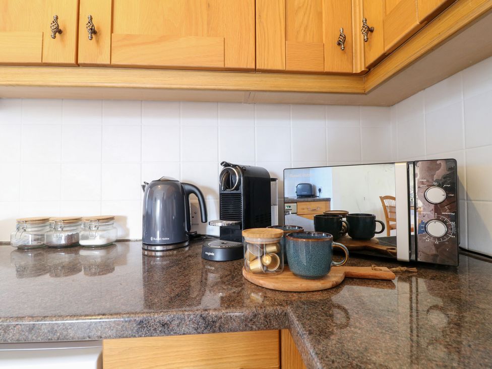 A kitchen counter with a kettle, coffee machine, microwave, and cups at The Hereford Lodge Great Haywood