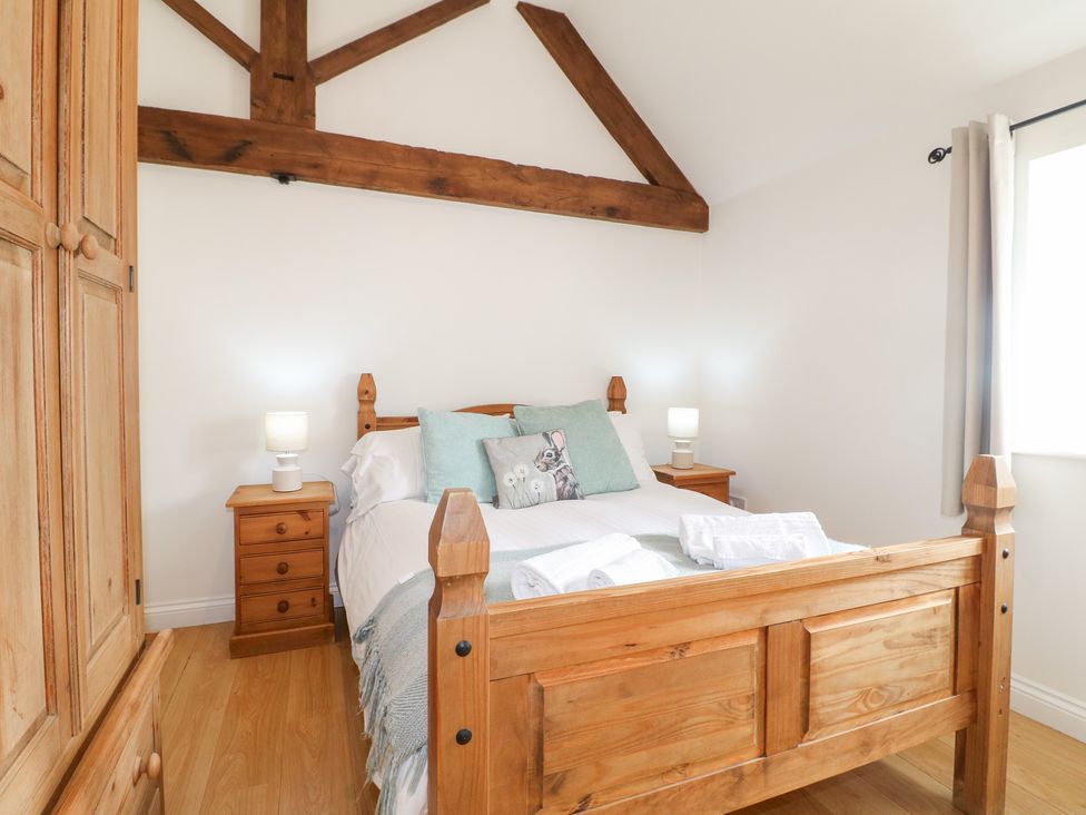 A bedroom with a wooden bed and nightstands at The Hereford Lodge in Great Haywood