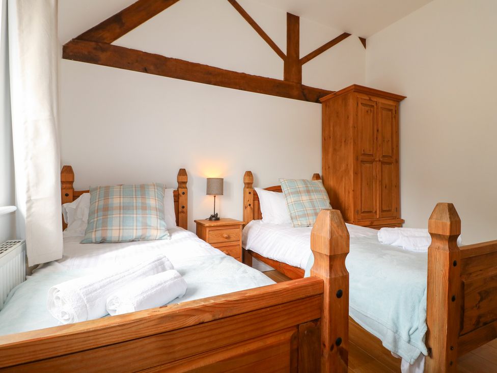 A bedroom with two beds and a wardrobe at The Hereford Lodge in Great Haywood