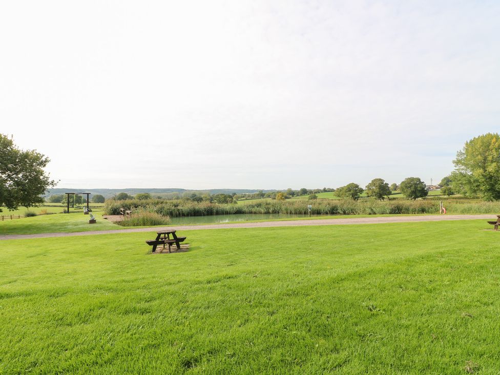 A picnic area with picnic tables and a pond at The Hereford Lodge Great Haywood