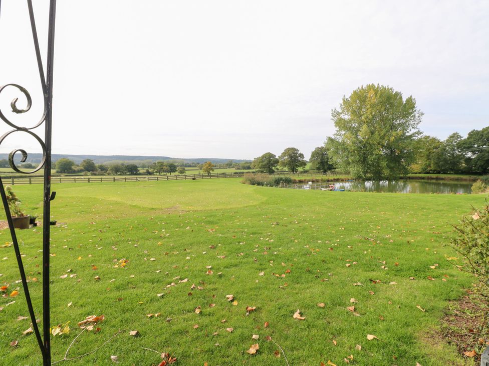 A garden with a pond and trees at The Hereford Lodge in Great Haywood