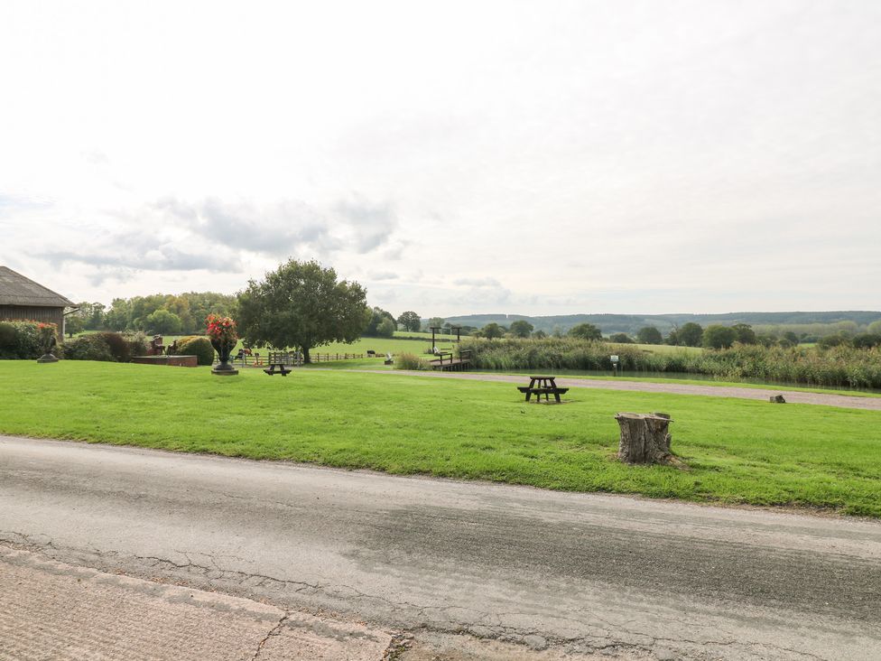 An outdoor area with grass, trees, and a picnic table at The Hereford Lodge in Great Haywood