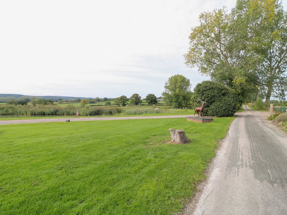 An outdoor area with grass, road, trees, and a sculpture at The Hereford Lodge in Great Haywood