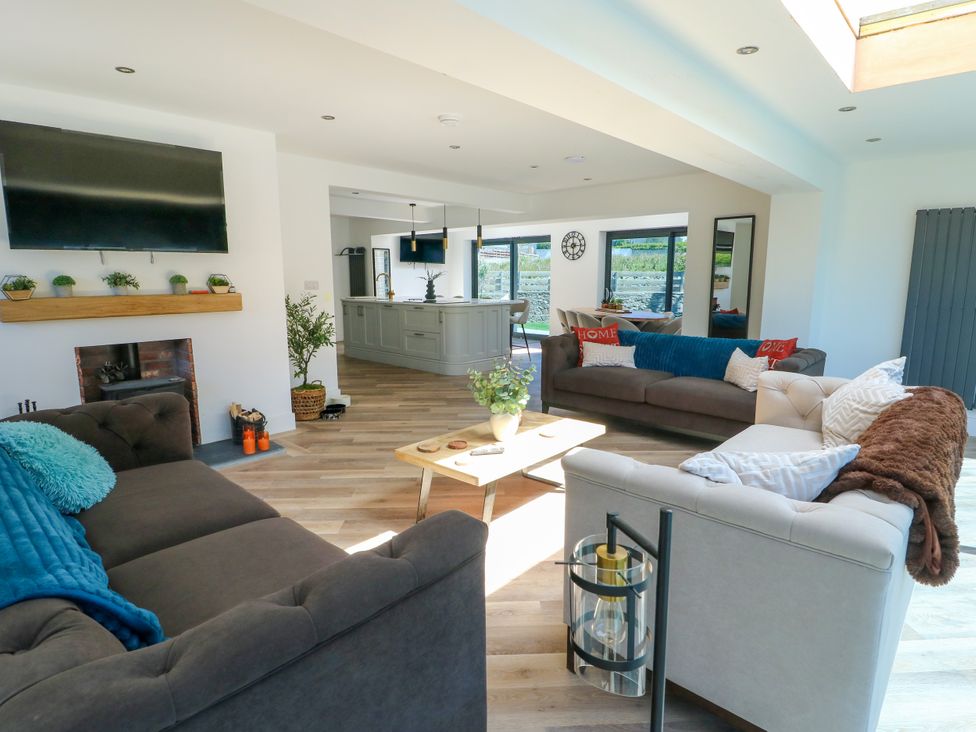A living room with a television and fireplace at Iscoed Rhosneigr