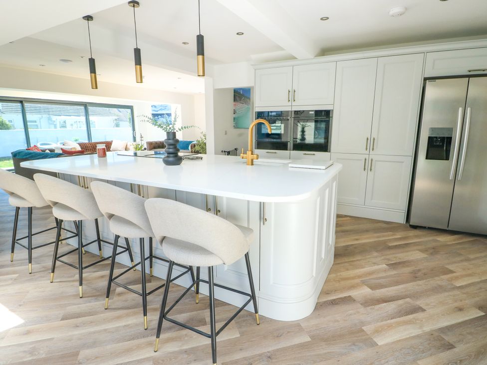 A kitchen with a large island and bar stools at Iscoed in Rhosneigr