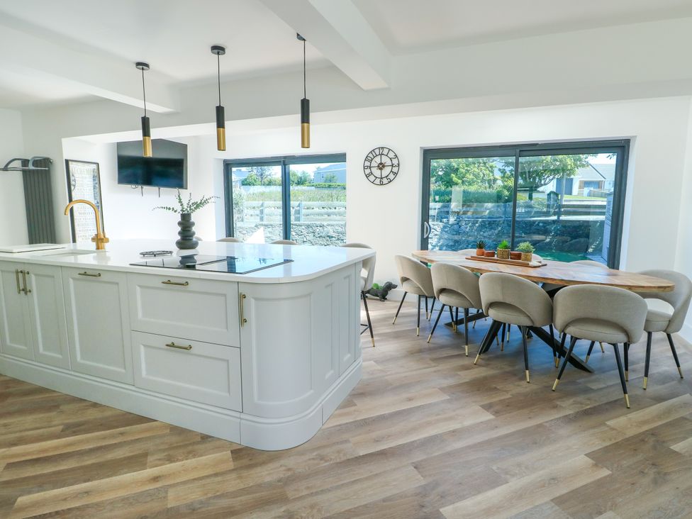 A kitchen with an island and dining area at Iscoed in Rhosneigr