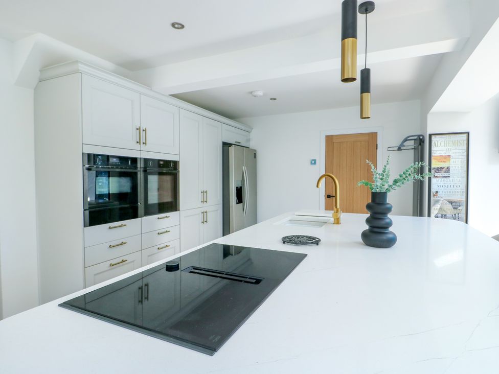 A kitchen with cabinets and appliances at Iscoed Rhosneigr