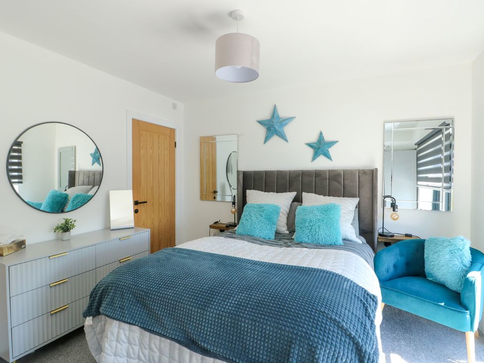 A bedroom with a bed and nightstand at Iscoed Rhosneigr