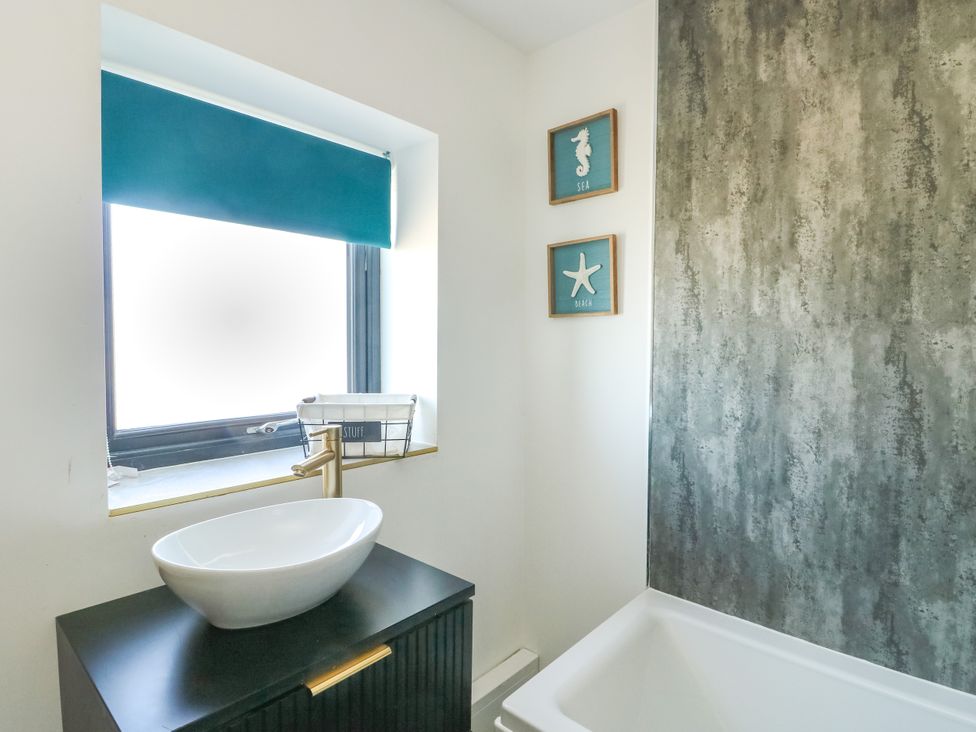 A bathroom with a sink and wall art at Iscoed in Rhosneigr