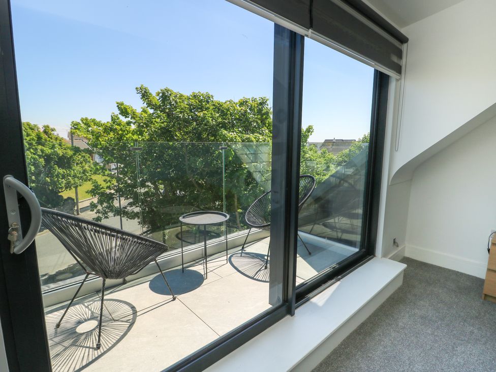 A balcony with chairs and a table at Iscoed Rhosneigr
