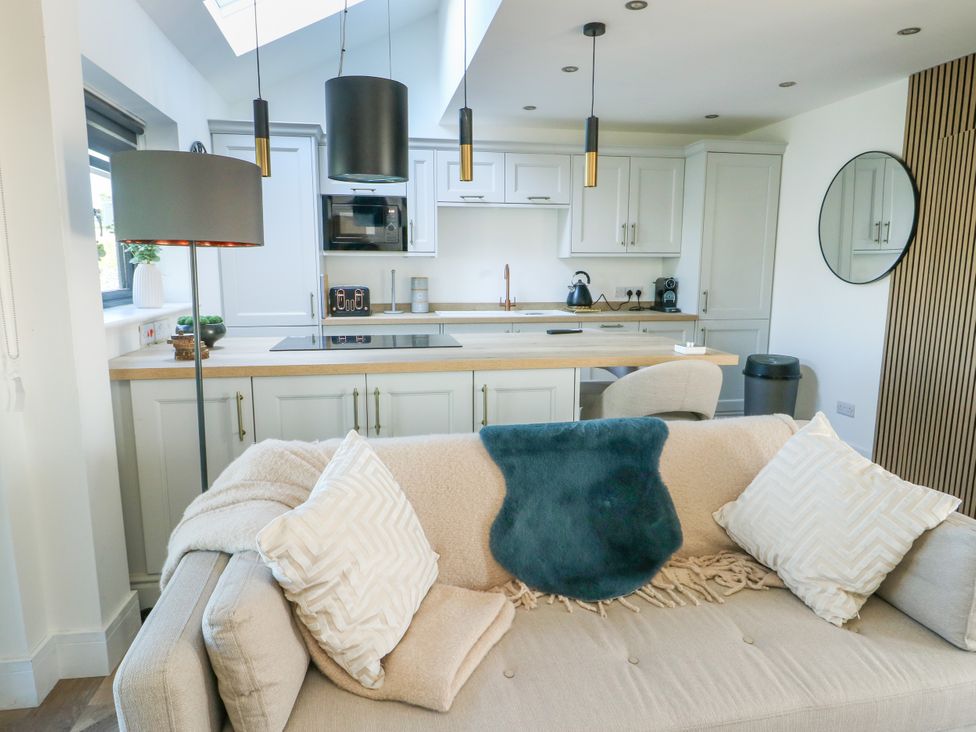 A living room with a kitchen countertop and sofa at Iscoed Rhosneigr
