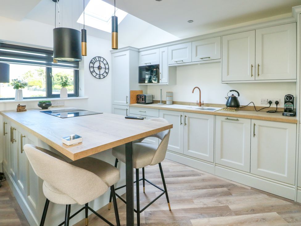 A kitchen with an island and stools at Iscoed in Rhosneigr
