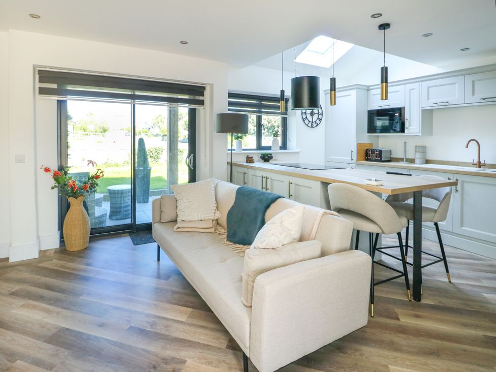 A living room and kitchen with a sofa and dining table at Iscoed Rhosneigr