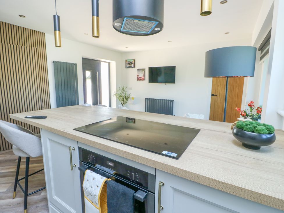 A kitchen with a stove and flower arrangement at Iscoed Rhosneigr