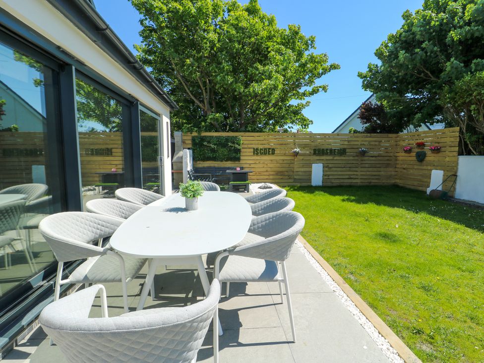 An outdoor dining area with a table and chairs at Iscoed Rhosneigr