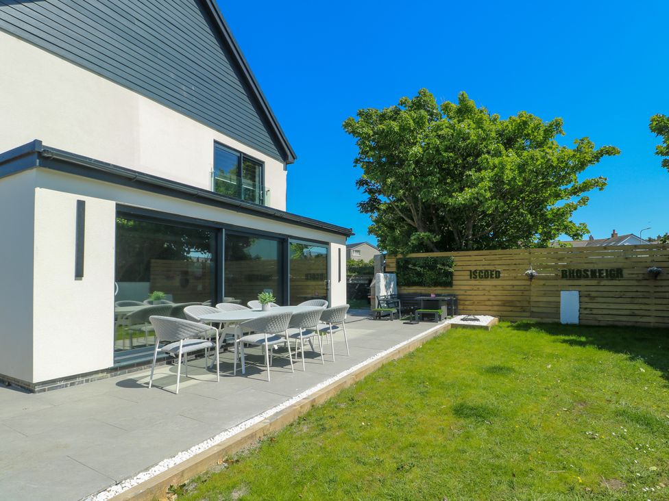 A garden area with a table and chairs at Iscoed Rhosneigr