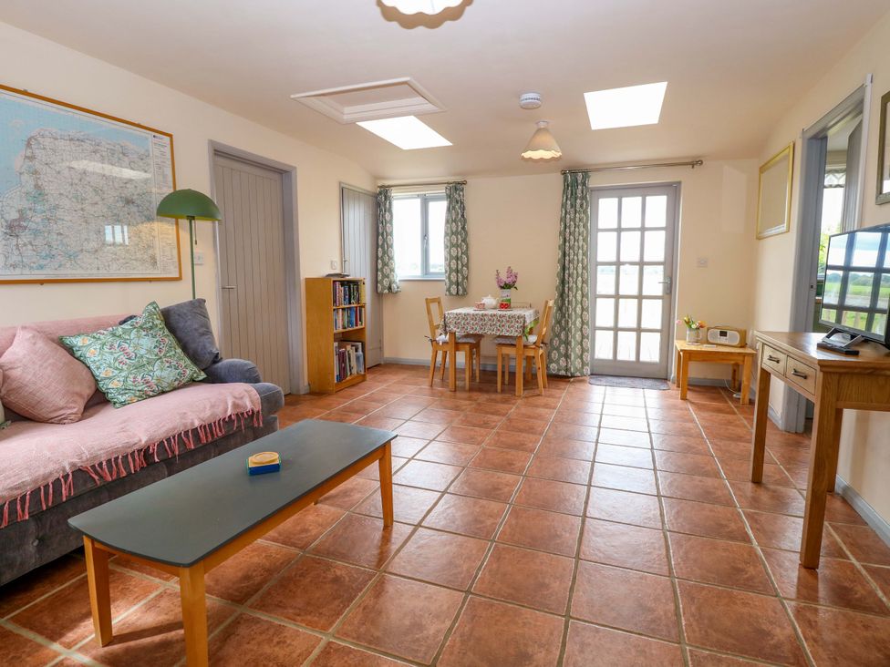 A living room with a sofa and dining area at Foxglove in King's Lynn