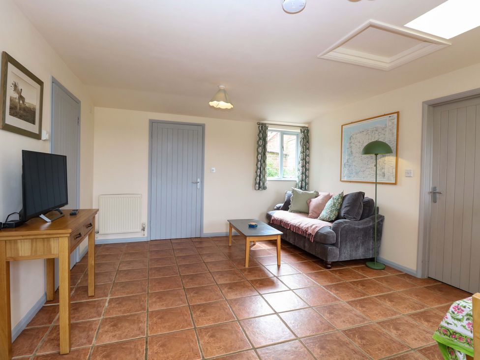 A living room with a sofa and television at Foxglove in King's Lynn