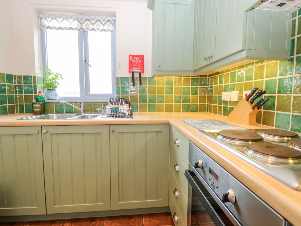 A kitchen with stove, sink, and cabinets at Foxglove in King's Lynn