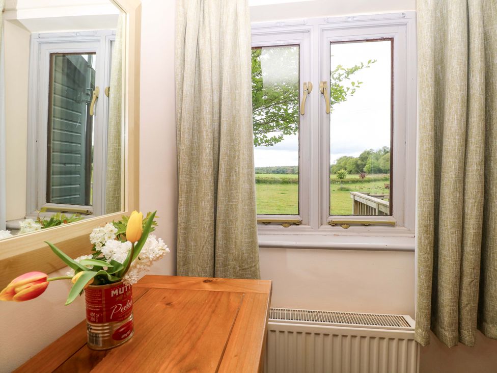 A room with a window and flowers on a table at Foxglove in King's Lynn