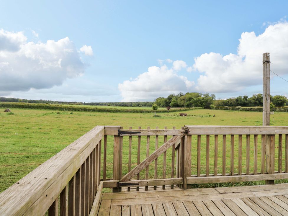 A wooden deck with an open gate overlooking a field at Foxglove in King's Lynn