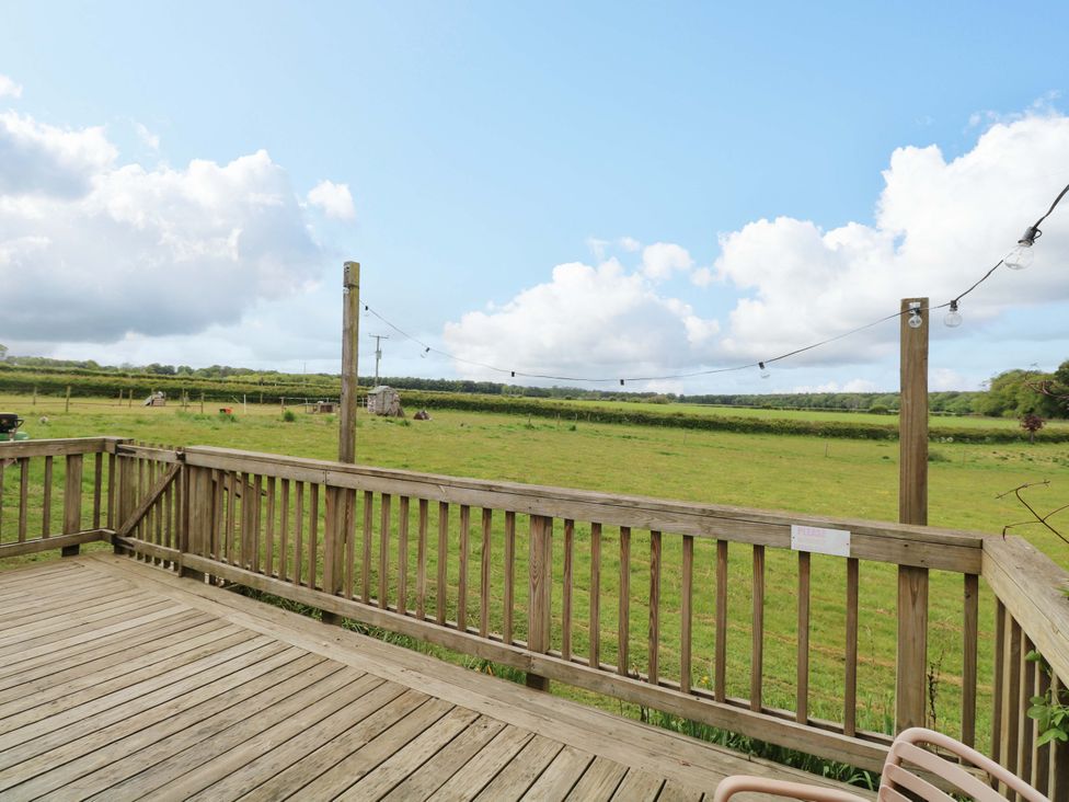 An outdoor area with a wooden deck overlooking a grassy field at Foxglove in King's Lynn