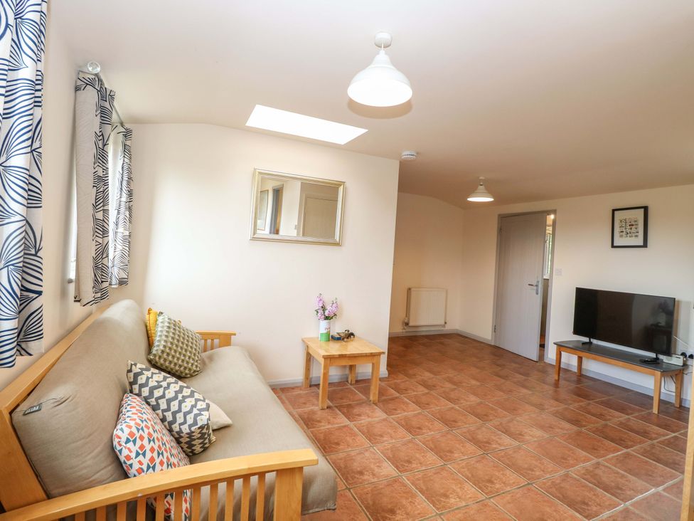 A living room with a sofa and TV at Hollyhock in King's Lynn