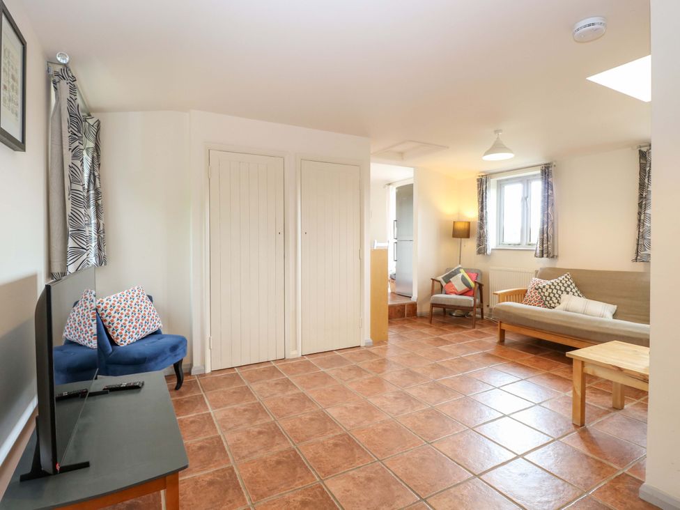 A living room with a sofa and television at Hollyhock in King's Lynn