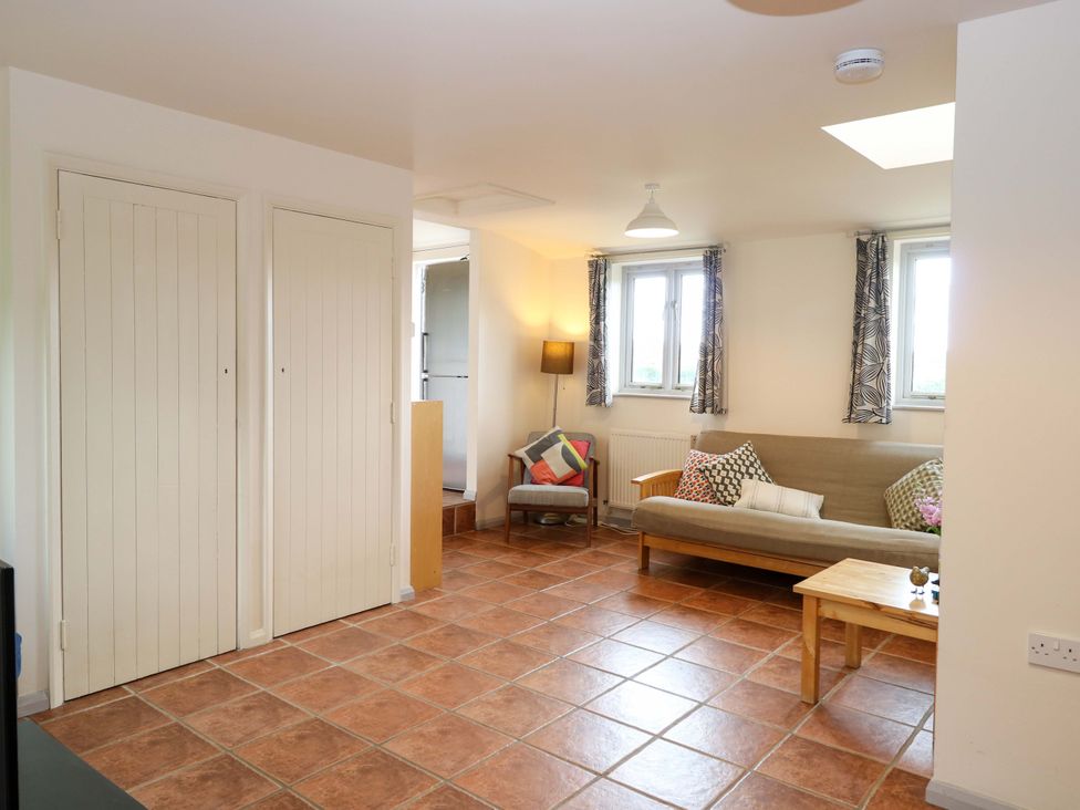 A living room with a sofa, lamp, and doors at Hollyhock in King's Lynn
