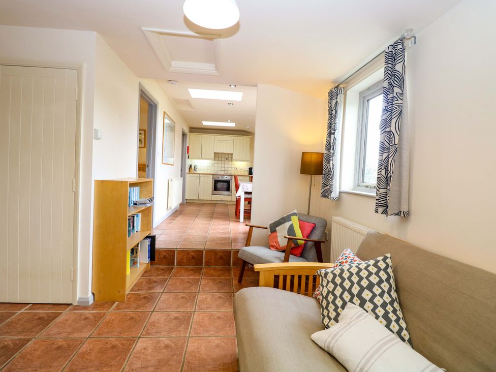 A living room with a sofa and bookshelf at Hollyhock in King's Lynn