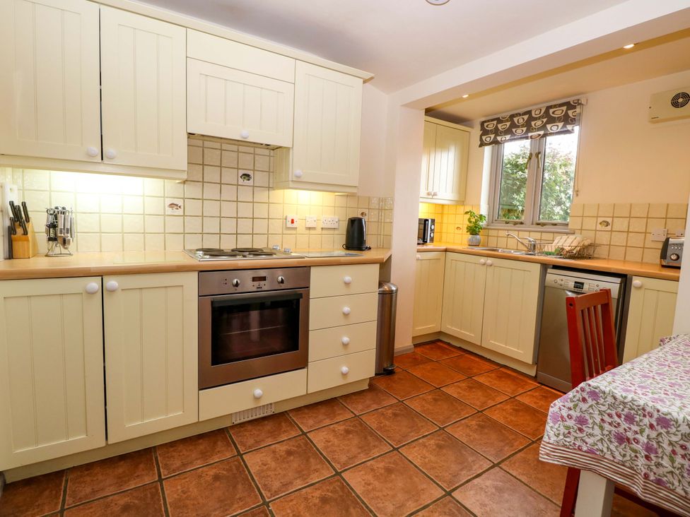 A kitchen with cabinets, oven, sink, and table at Hollyhock in King's Lynn