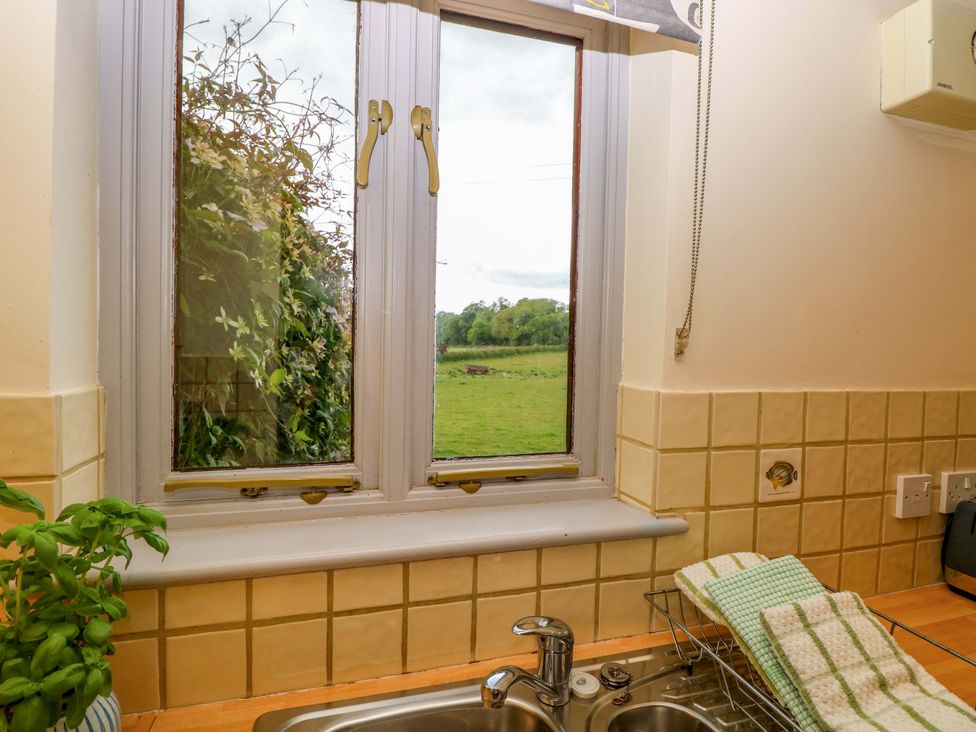 A kitchen with a sink and window overlooking the countryside at Hollyhock in King's Lynn