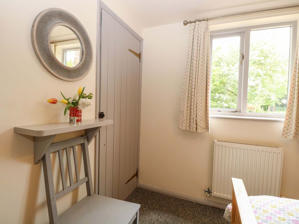 A bedroom with a chair and mirror at Hollyhock in King's Lynn