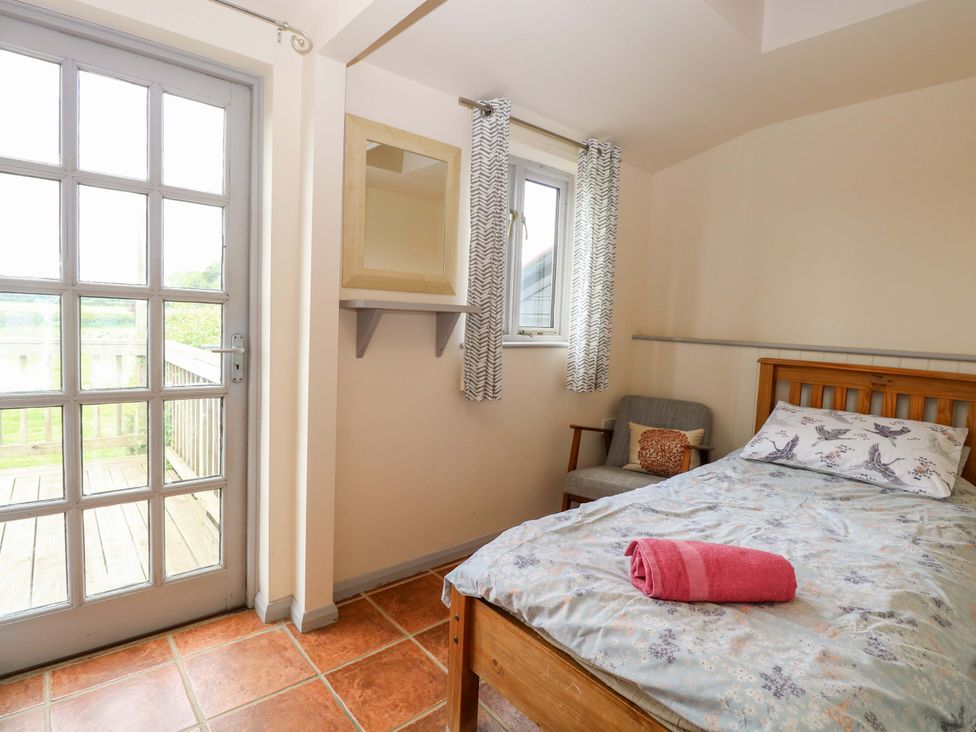 A bedroom with a bed, chair, and window at Hollyhock in King's Lynn