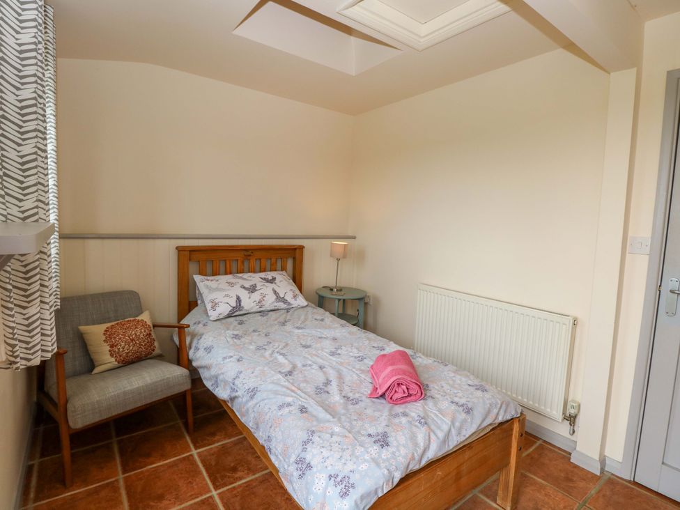A bedroom with a bed, chair, and lamp at Hollyhock in King's Lynn