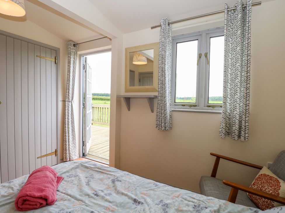 A bedroom with a bed and a door leading outside at Hollyhock in King's Lynn
